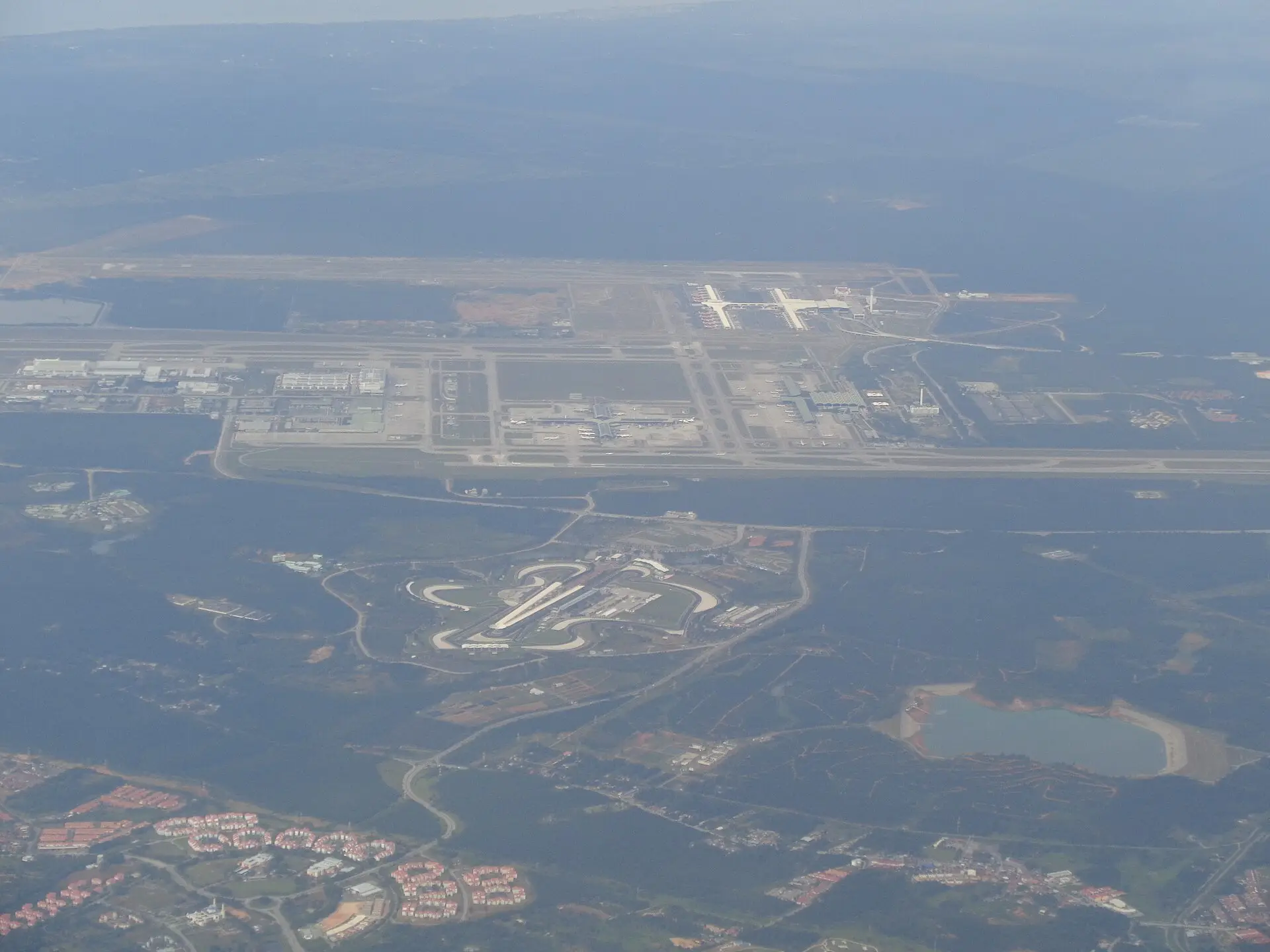 Aerial view showing Kuala Lumpur International Airport runways and terminals directly adjacent to Sepang International Circuit