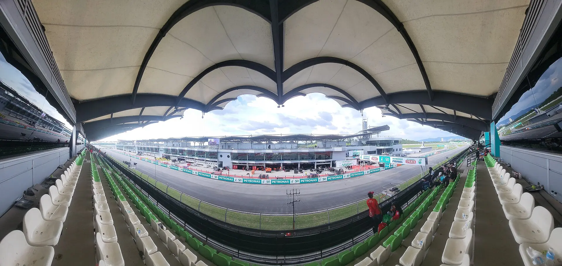 View from inside the main grandstand at Sepang, looking up at the scalloped tensile canopy and out across the pit lane and main straight